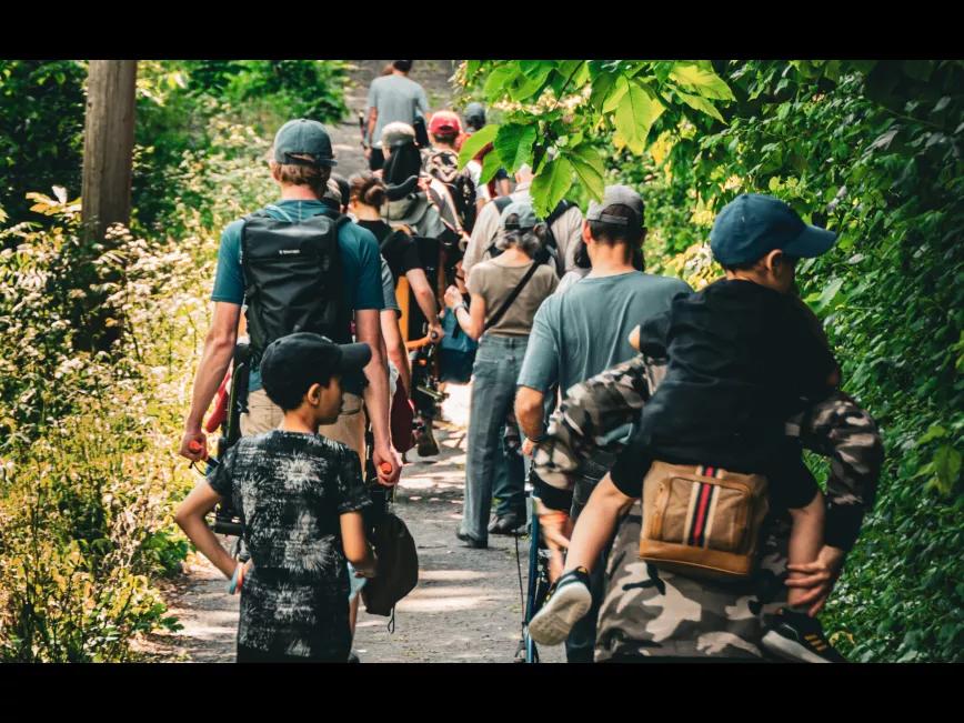 Un groupe de proches aidants se promène dans le bois, entourés d'une atmosphère paisible. Des enfants et des adultes, unis par le soutien mutuel, profitent de cette sortie en nature.